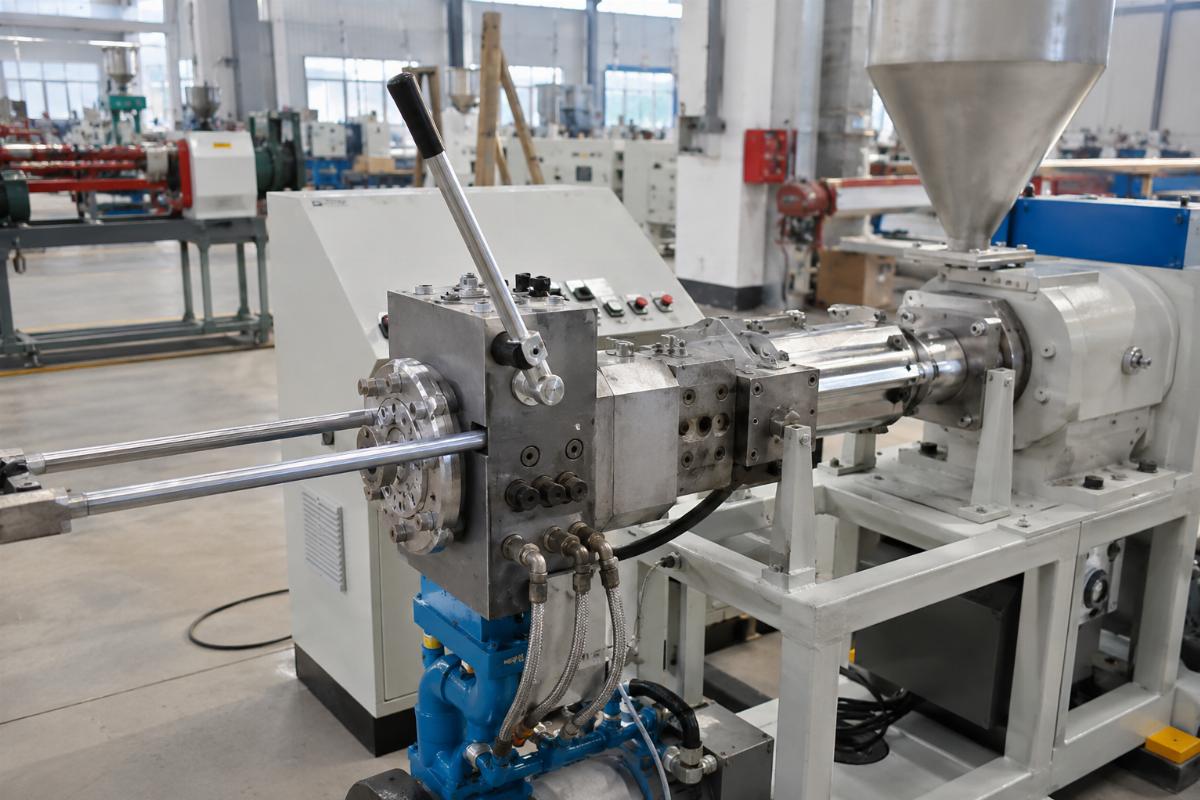 A factory floor showing a manual screen changer installed on a small to mid-sized extrusion line